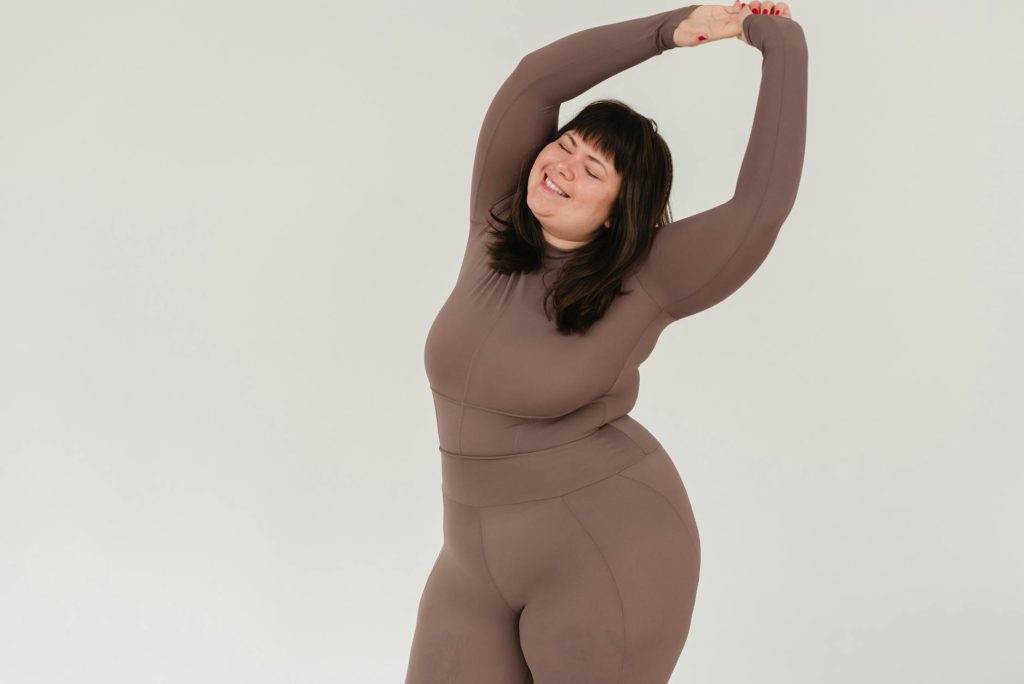 overweight smiling woman in sportswear with raised arms